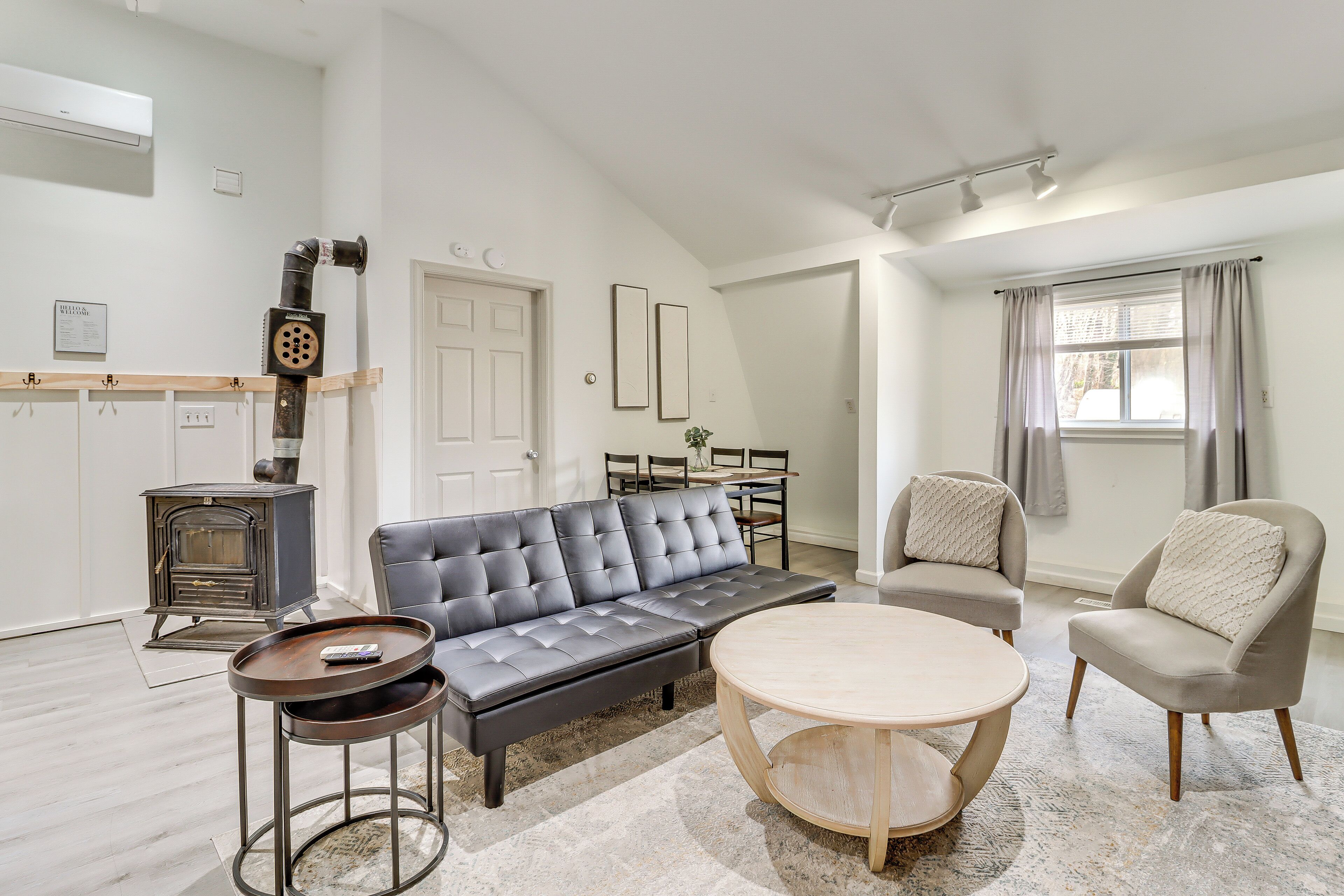 Un salon moderne comprenant un canapé, deux fauteuils, une table basse et un poêle d’époque.