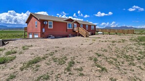 A red two-story house with a wooden deck and a staircase leading to the front door. - Mtn Gem w/ Breathtaking Scenery: 7 Mi to Dtwn (Del Norte)