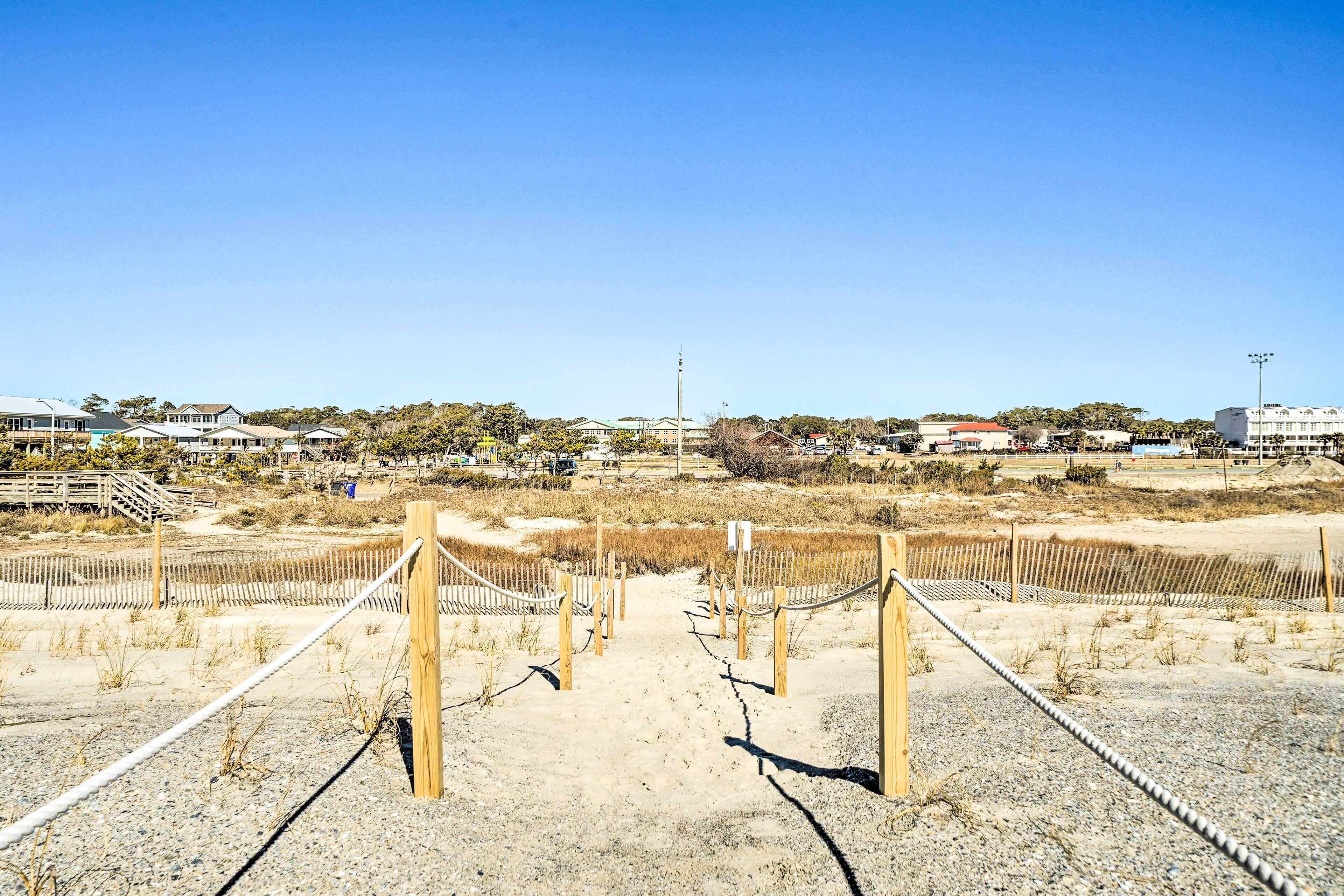 A sandy beach area with wooden fences and a clear sky.