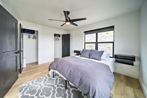 A bedroom with a bed, a ceiling fan, a window, and a wardrobe.