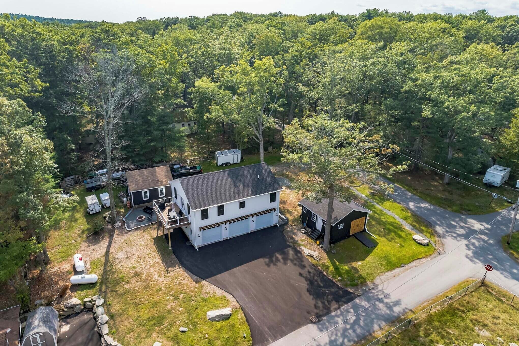 A two-story house with a garage, surrounded by a wooded area.