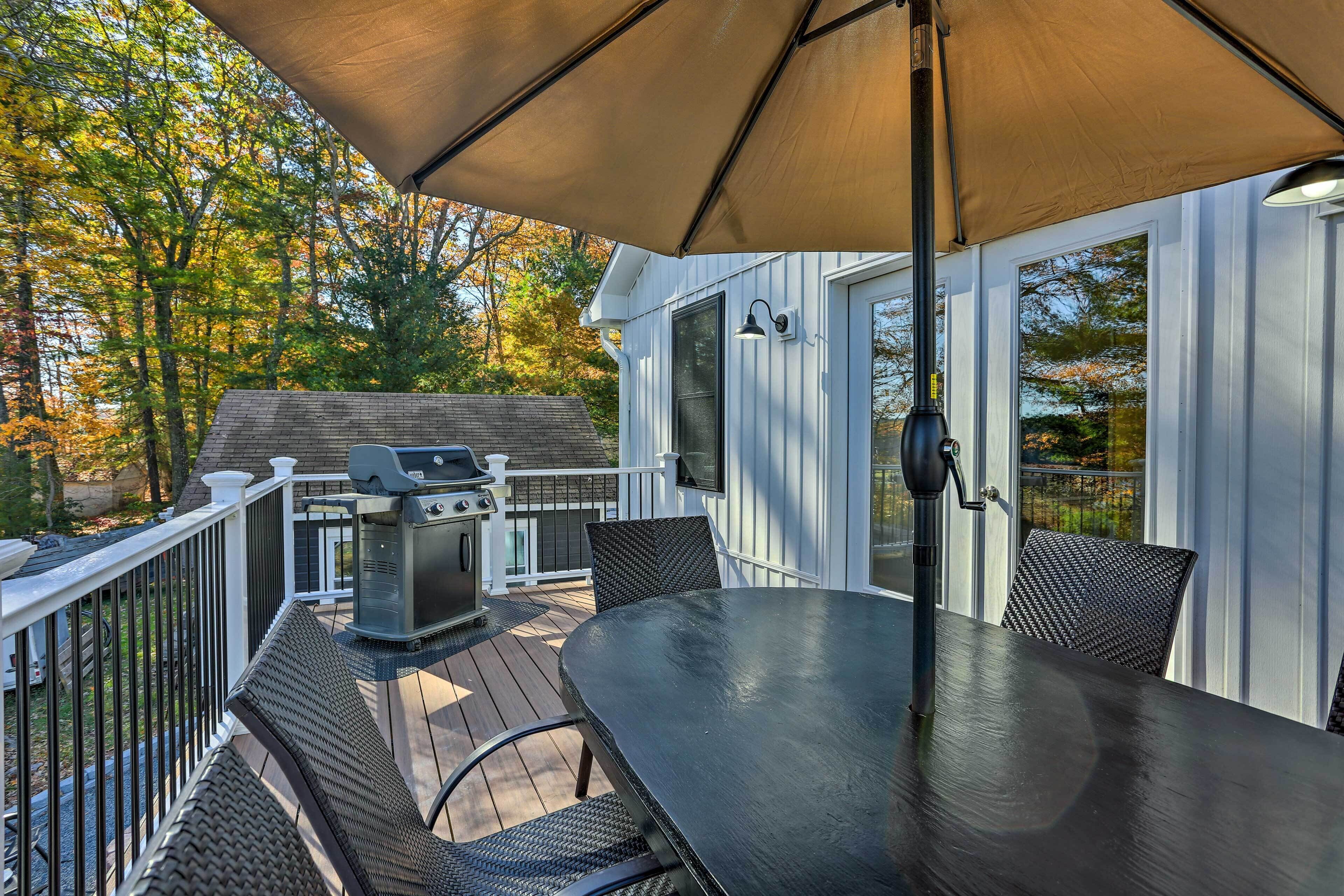 A covered outdoor patio with a grill, dining table, and chairs.