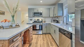 Een moderne keuken met roestvrijstalen apparatuur, lichtgrijze kastjes en een houten vloer.