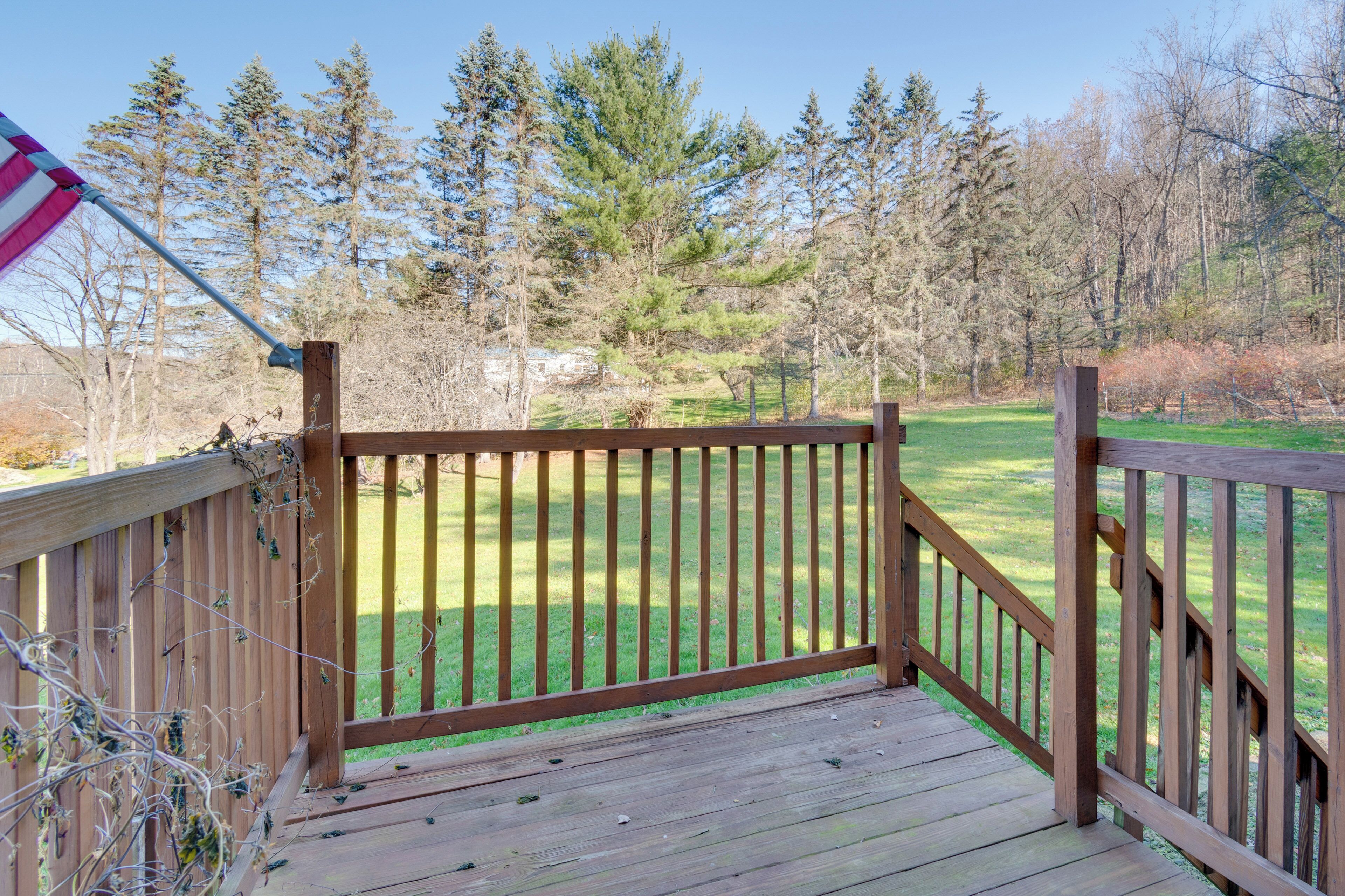 A wooden deck with a railing overlooking a grassy area with trees.