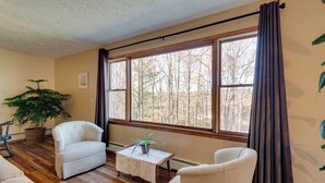 A living room with a large window, a potted plant, two chairs, and a small table. - Peaceful Horseheads Hideaway w/ Deck & Yard! (Horseheads)