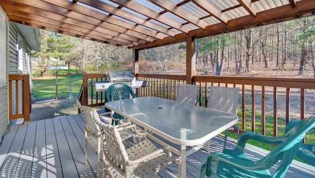 A covered outdoor deck with a table and chairs, a grill, and a view of a wooded area. - Peaceful Horseheads Hideaway w/ Deck & Yard! (Horseheads)
