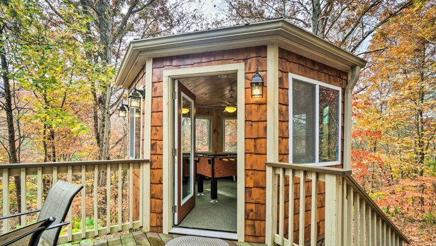 Een houten hut met een terras, een stoel en een deur naar binnen.