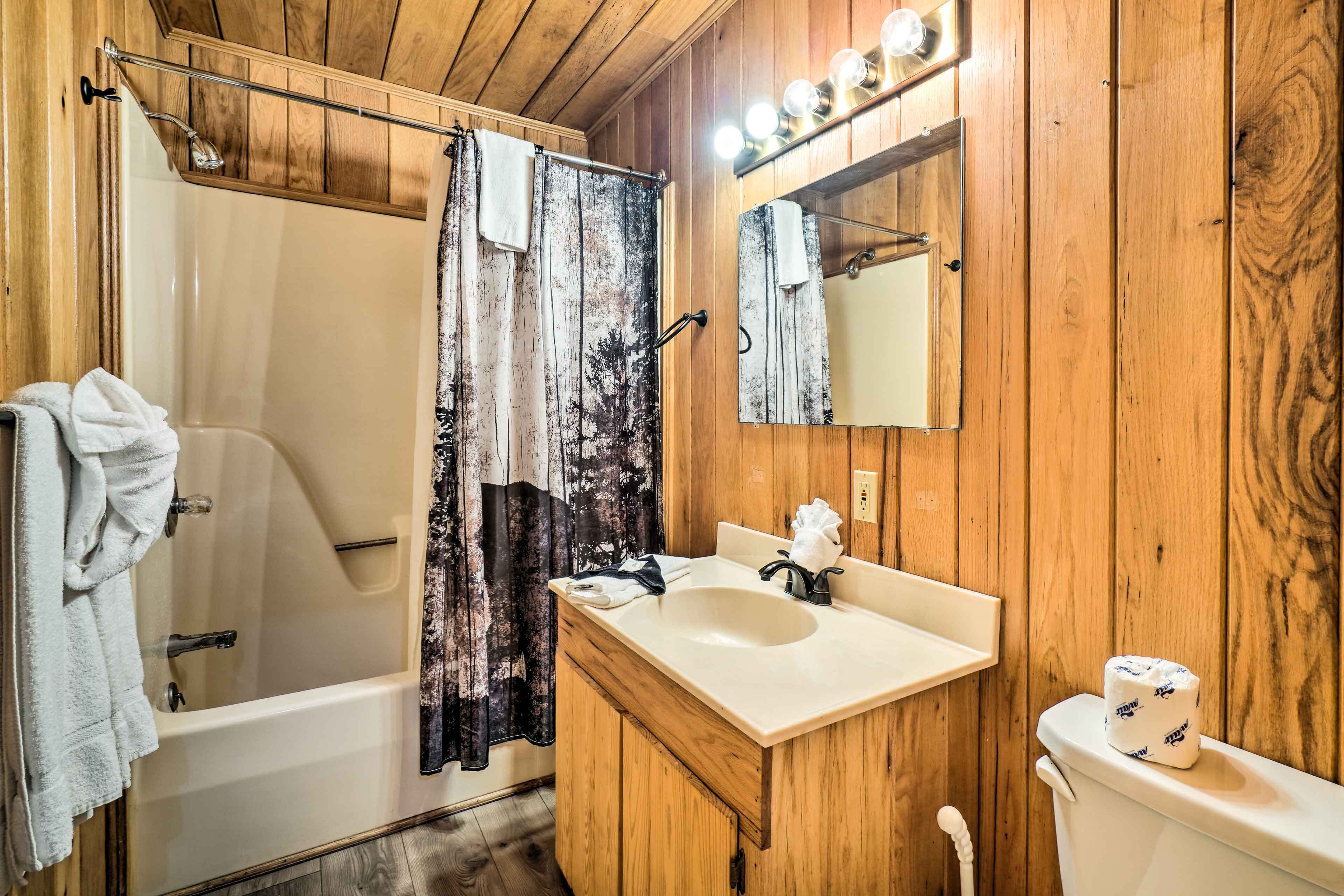 A wooden-paneled bathroom with a bathtub, a sink, and a toilet.