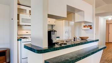 A modern kitchen with white cabinets, a stainless steel sink, and a marble countertop.
