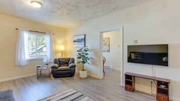 A living room with a sofa, a coffee table, a TV, and a potted plant.
