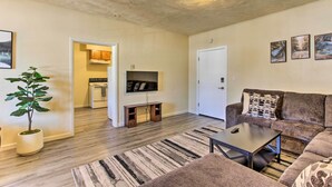 A living room with a brown sofa, a coffee table, a TV on a stand, a plant, and a patterned rug. - Oregon Getaway by Willamette National Forest! (Oakridge)