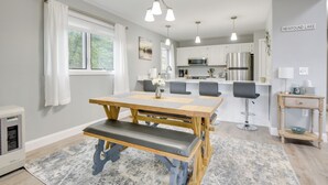 A modern kitchen with white cabinets, stainless steel appliances, and a wooden dining table with benches.