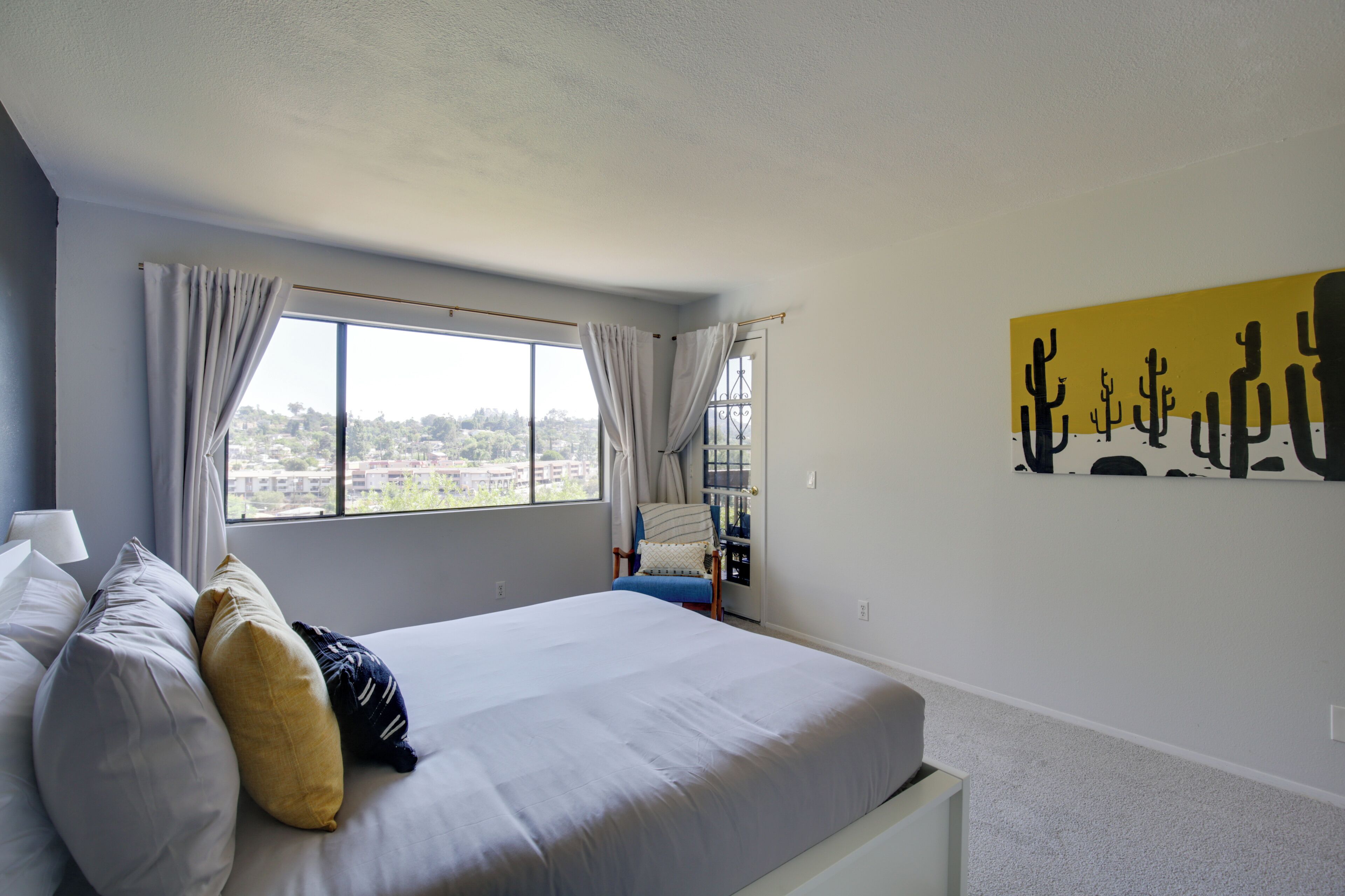 Un dormitorio con una cama grande, vistas a la ciudad y una decoración de pared con motivos desérticos.