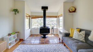 Una sala de estar con chimenea, un sofá, una mesa de centro y vistas amplias a través de grandes ventanales.