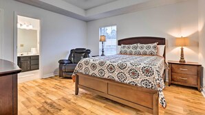 A bedroom with a wooden bed, a chair, a nightstand, a lamp, a mirror, and a window. - Ocean Springs Home w/ Sunroom ~ 5 Mi to Beach (Ocean Springs)