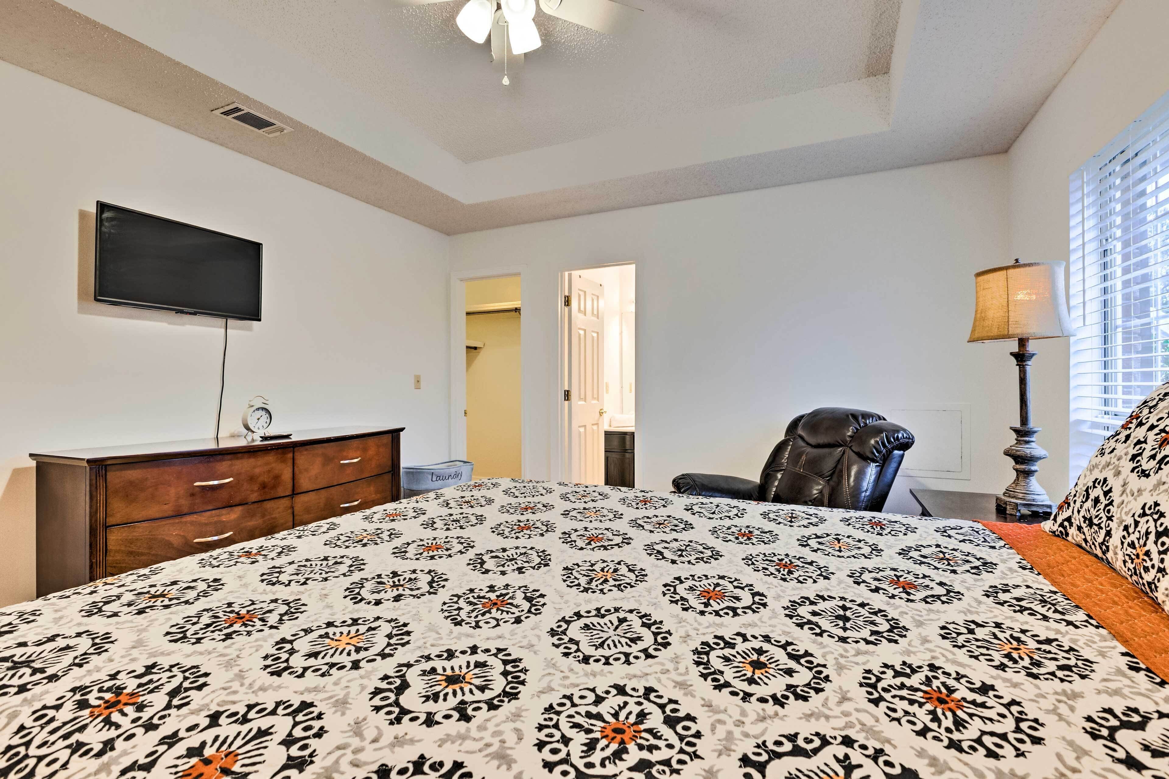 A bedroom with a bed, a TV, a dresser, a chair, and a lamp.