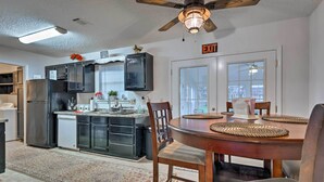 A modern kitchen with dark cabinets, a built-in oven, and a dining area with a wooden table and chairs. - Ocean Springs Home w/ Sunroom ~ 5 Mi to Beach (Ocean Springs)