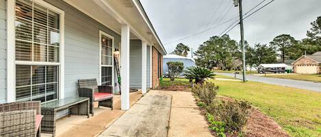 A house with a covered porch, outdoor furniture, and a clear view of the street.