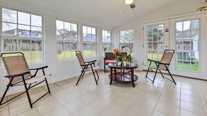 A sunroom with large windows, a ceiling fan, and two folding chairs around a central table with a vase of flowers. - Ocean Springs Home w/ Sunroom ~ 5 Mi to Beach (Ocean Springs)