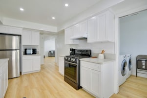 Una cocina moderna con gabinetes blancos, electrodomésticos de acero inoxidable y una isla central.