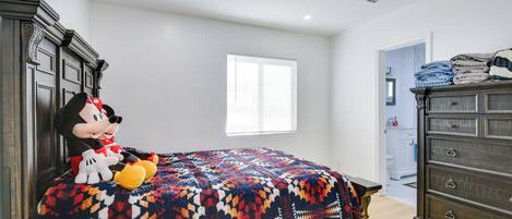Quarto com uma cama, penteadeira e um boneco de pelúcia do Mickey Mouse.