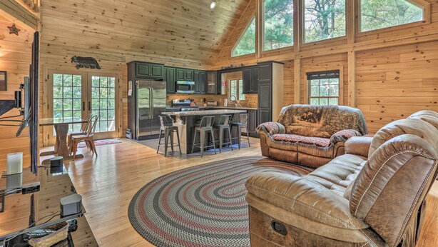 A spacious log cabin interior with a kitchen, dining area, and seating.