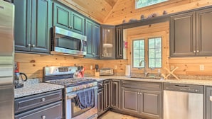 A modern kitchen with dark cabinets, stainless steel appliances, and a granite countertop.