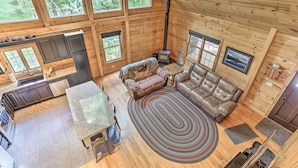 A spacious cabin with a kitchen, dining area, and living room. It features large windows, a fireplace, and a cozy seating area.