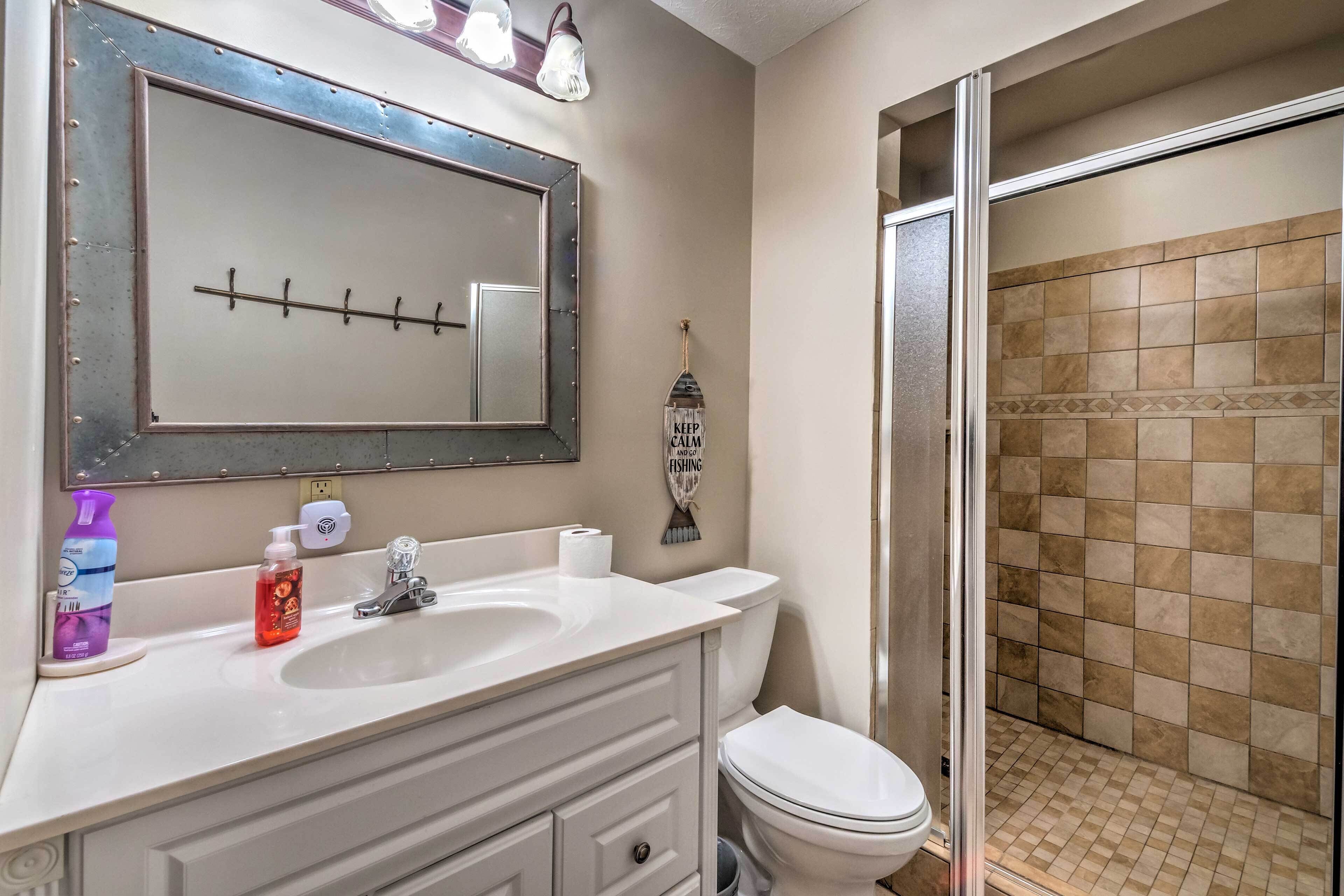 A bathroom with a large mirror, a sink, a toilet, and a shower area.
