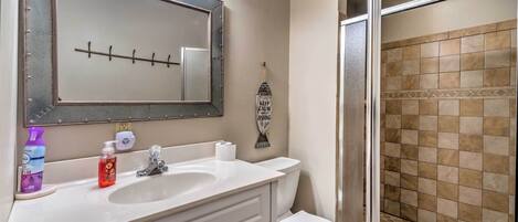 A bathroom with a large mirror, a sink, a toilet, and a shower area.
