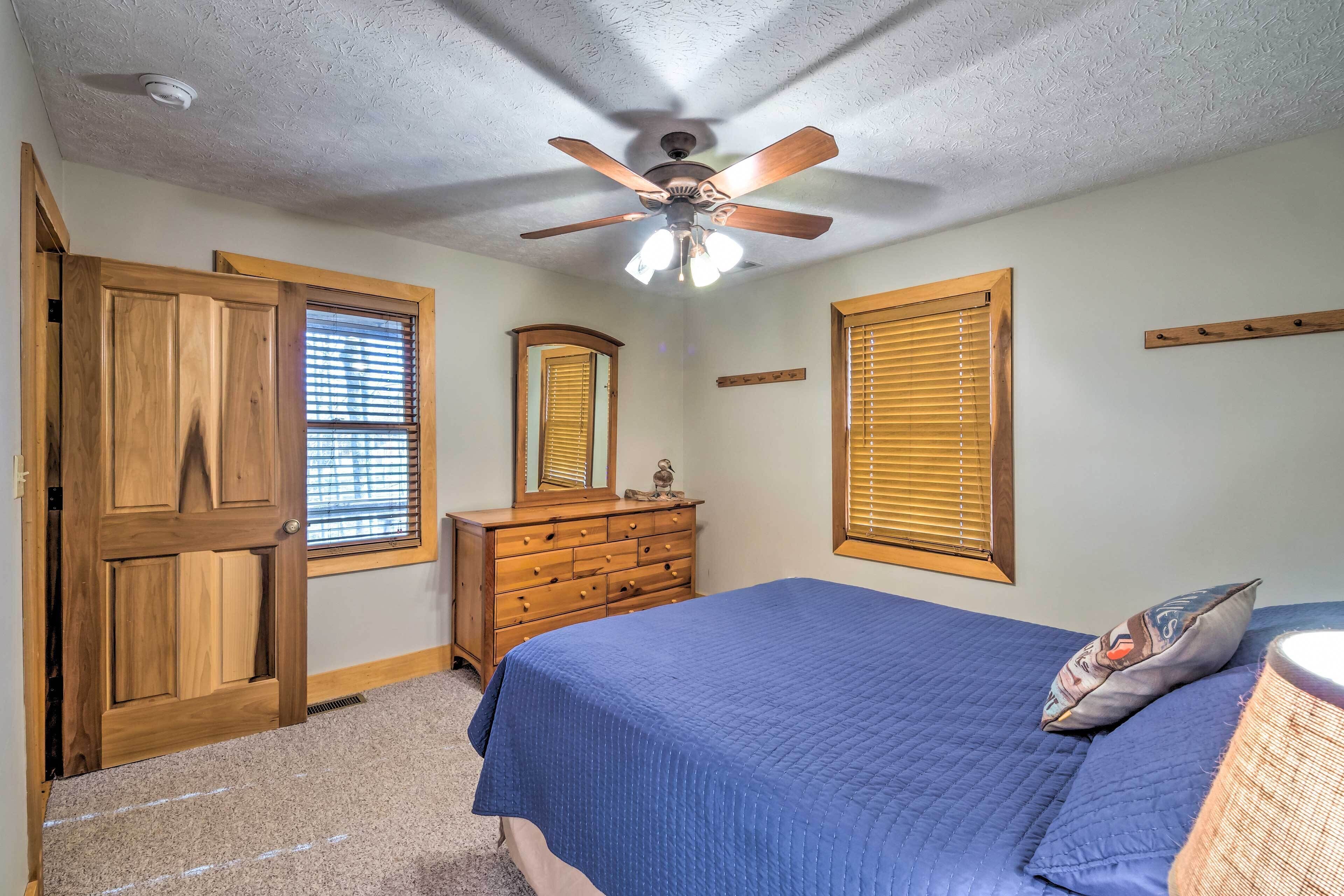 A bedroom with a bed, wooden dresser, and a ceiling fan.