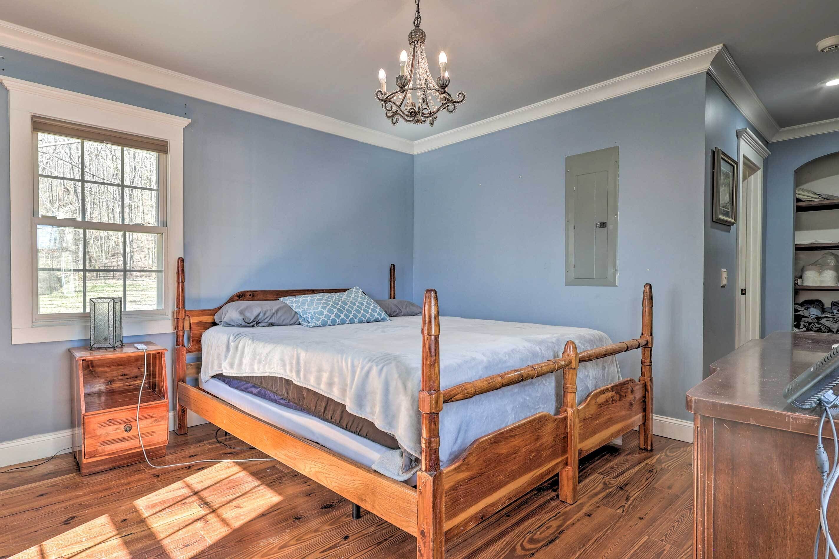 A bedroom with a wooden bed, a nightstand, a dresser, and a chandelier.