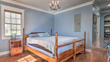 A bedroom with a wooden bed, a nightstand, a dresser, and a chandelier.