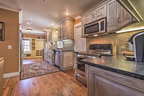 A kitchen with wooden cabinets, stainless steel appliances, and a brick backsplash. - Secluded Getaway Home w/ Trails + Waterfall! (Falkville)