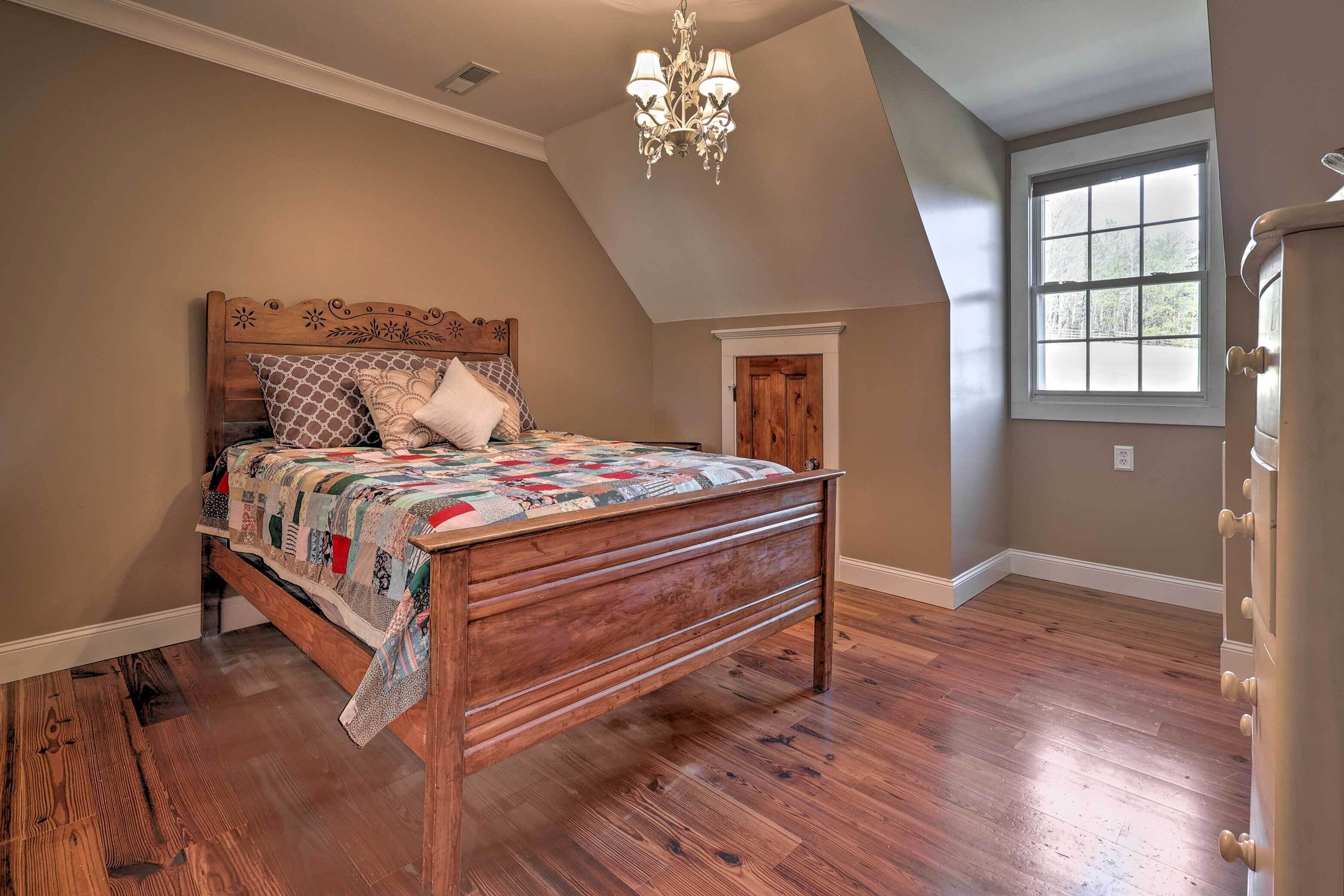 A bedroom with a wooden bed, a chandelier, a window, and a door.