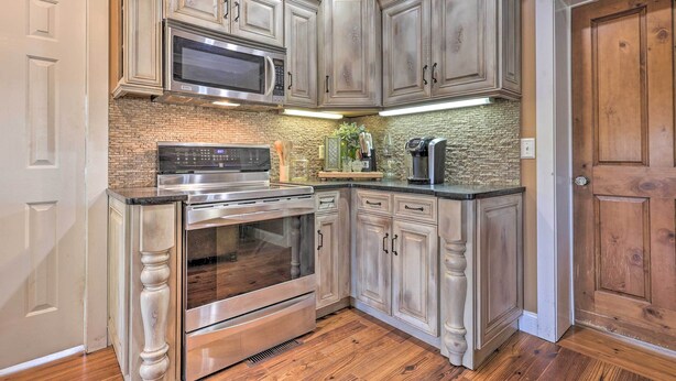 Una cucina con mobili in legno, forno in acciaio inossidabile, microonde e zoccolo in mattoni.
