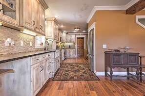 A kitchen with wooden cabinets, a brick backsplash, and a patterned rug. - Secluded Getaway Home w/ Trails + Waterfall! (Falkville)