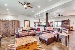 A spacious living room with a sectional sofa, wooden coffee table, and a decorative wall panel. - Pet Friendly 'daydreamers Guest Ranch' on 60 Acres (Lingle)