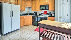 A kitchen with wooden cabinets, a white refrigerator, a microwave, a stove, and a wooden table. - Pet-friendly Lafayette Vacation Rental! (Lafayette)