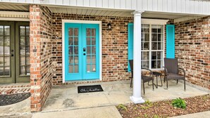 A brick building with a blue door and shutters, a porch with chairs, and a doormat. - Pet-friendly Lafayette Vacation Rental! (Lafayette)