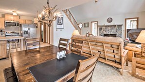 A spacious kitchen with wooden cabinets, a dining table, and a stone fireplace. - Walk to Beach: Lakefront Pocono Escape w/ Fire Pit (Pocono Lake)
