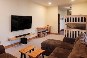 A living room with a flat-screen TV, wooden furniture, and a multi-level wooden structure. - Secluded Sapphire Chalet w/ Game Room + Decks (Sapphire)