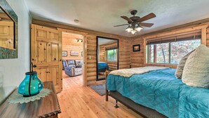Ein Schlafzimmer in einer Blockhütte mit einem Bett, einem Deckenventilator und Blick ins Freie.