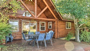 Eine Blockhütte mit einer Terrasse, Sitzgelegenheiten im Freien und großen Fenstern.