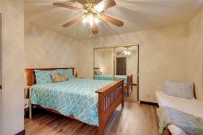 A bedroom with a wooden bed, a smaller bed, a ceiling fan, and a full-length mirror. - Serene Groveland Cabin Rental Near Yosemite! (Groveland)