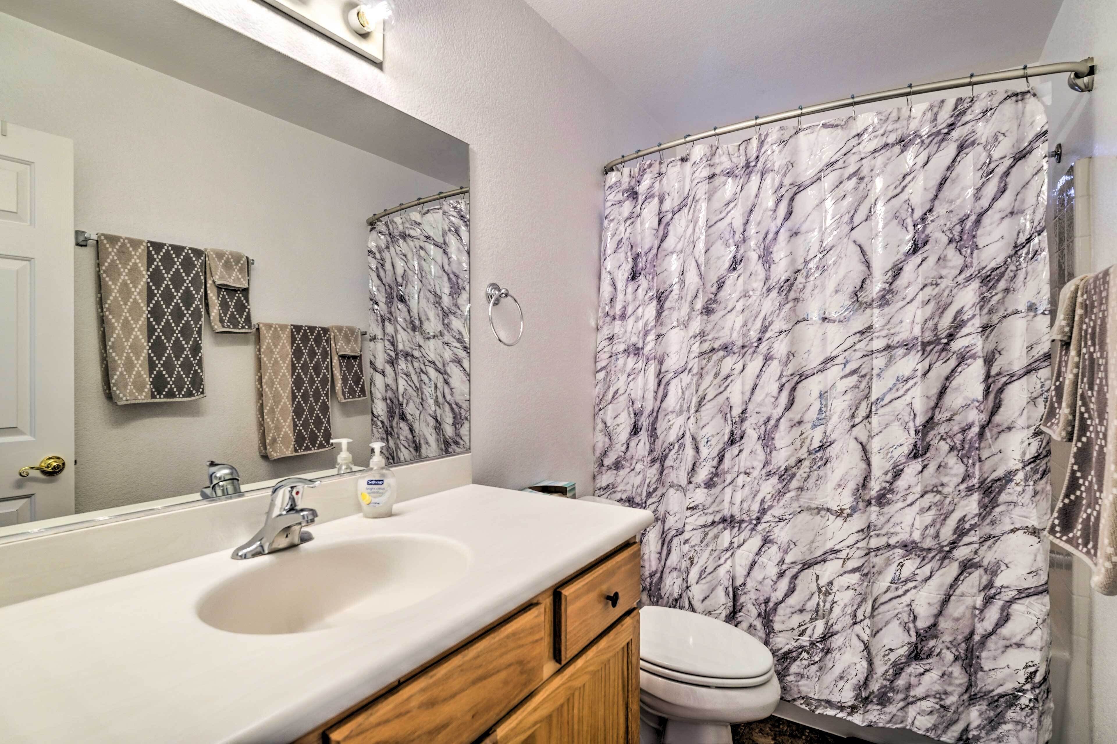 Une salle de bain avec un rideau de douche en marbre, un lavabo avec un miroir et des toilettes.