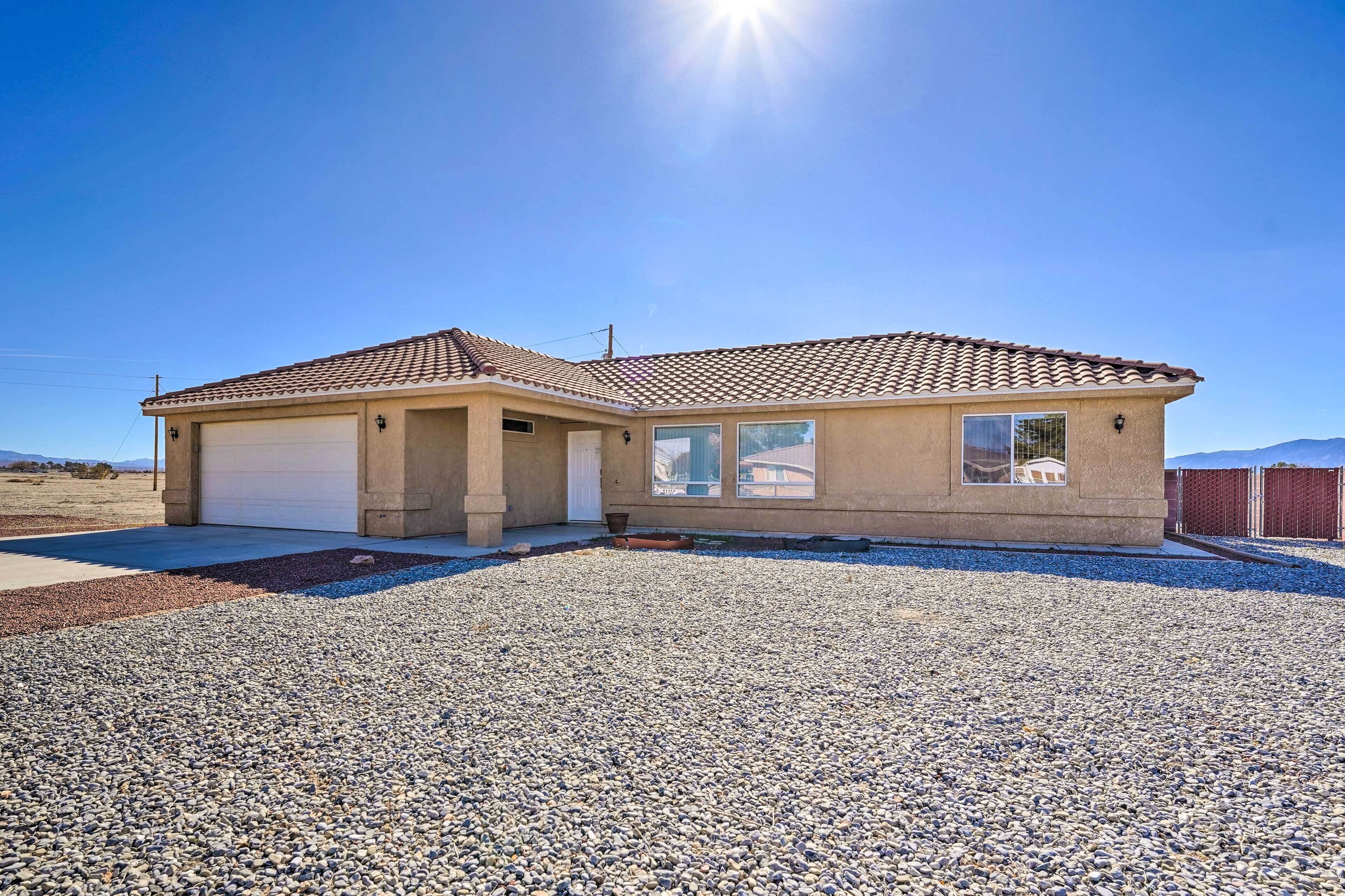 A single-story house with a garage, a small porch, and a gravel driveway.