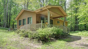 A wooden cabin with a porch and a staircase, surrounded by a forest. - Secluded Farwell Cabin w/ Fire Pit & Gas Grill! (Farwell)