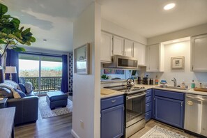A modern kitchen with stainless steel appliances, a blue countertop, and white cabinets.