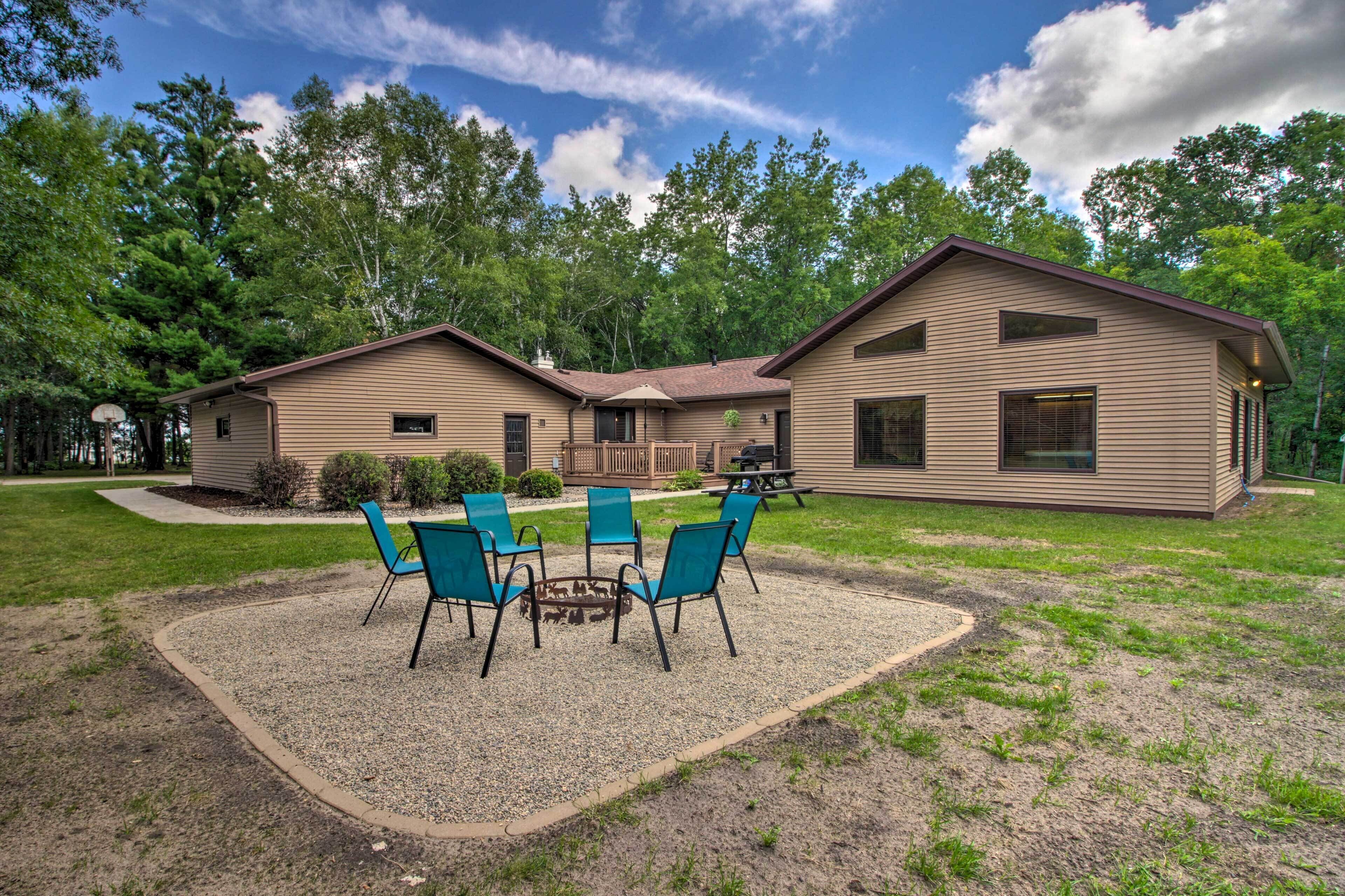 A two-story house with a patio area featuring four blue chairs and a small table.